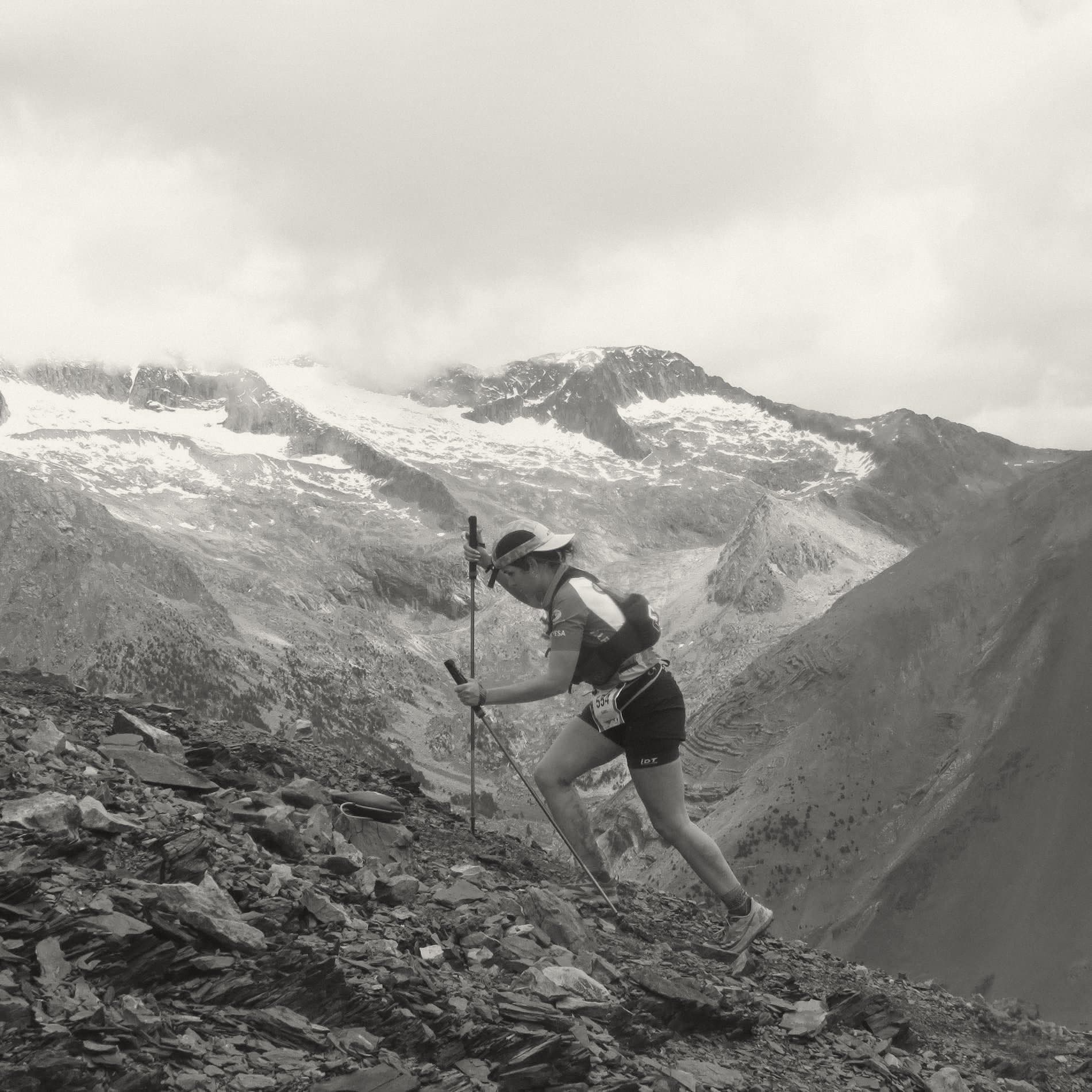Isa asciende por un sendero de alta montaña junto a un glaciar.